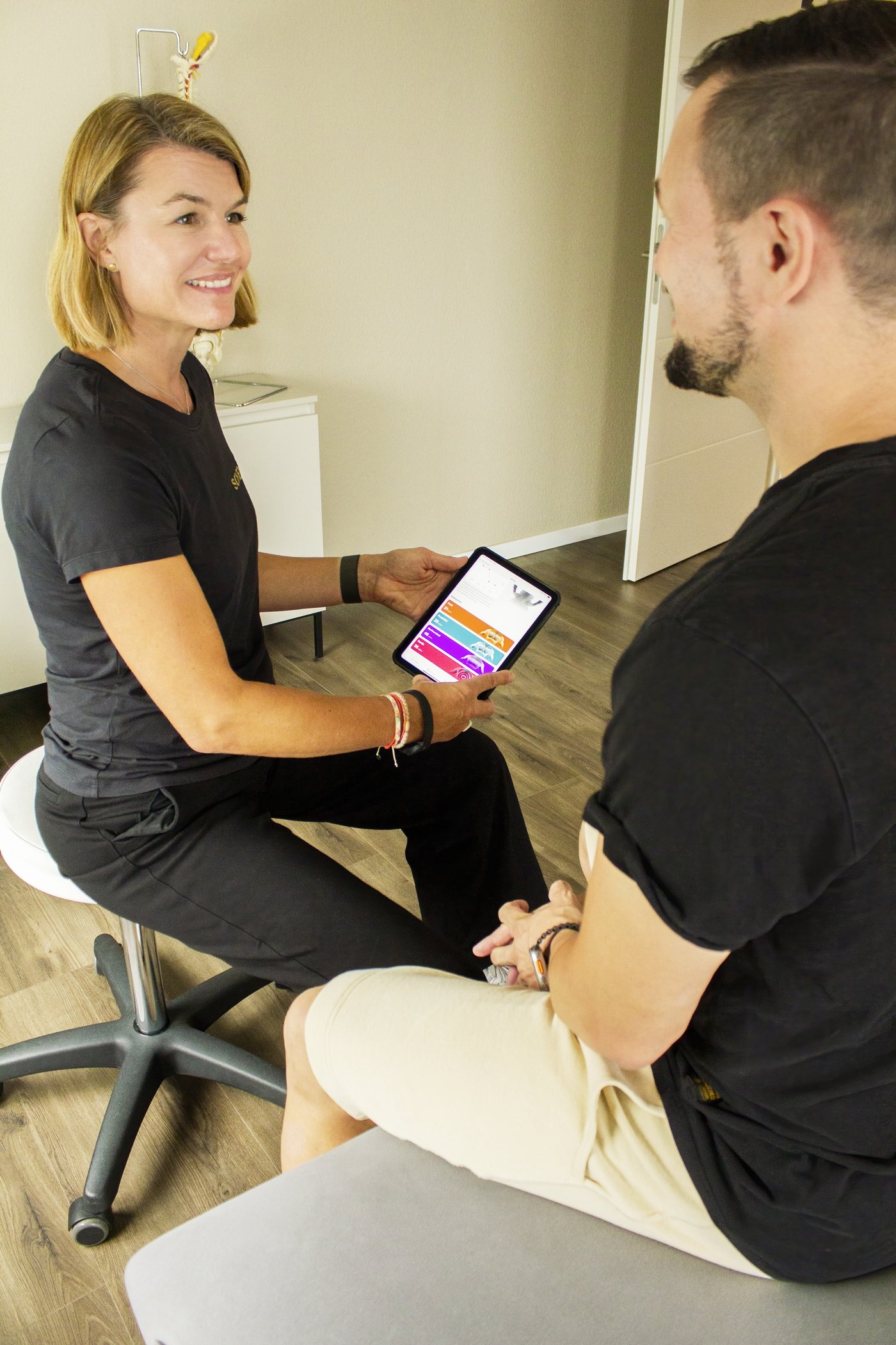 Physiotherapeutin bespricht den Befund mit einem Patienten am Tablet in Rösrath
